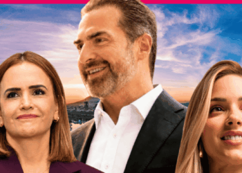 Three smiling adults in business attire pose against a sunset cityscape background.